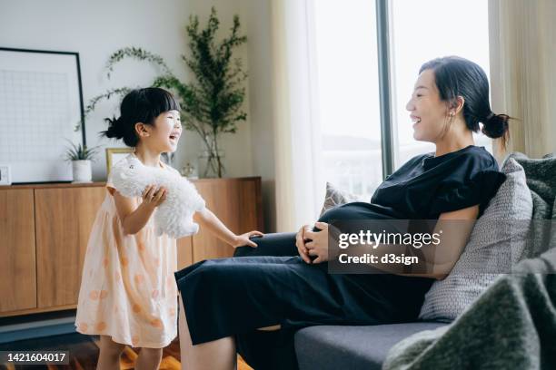 asian pregnant mother and lovely little daughter having a great time together. mother and daughter spending time chatting and playing at home, both of them are smiling joyfully. bonding between mother and daughter. family lifestyle. love and care concept - chinese mothers day - fotografias e filmes do acervo