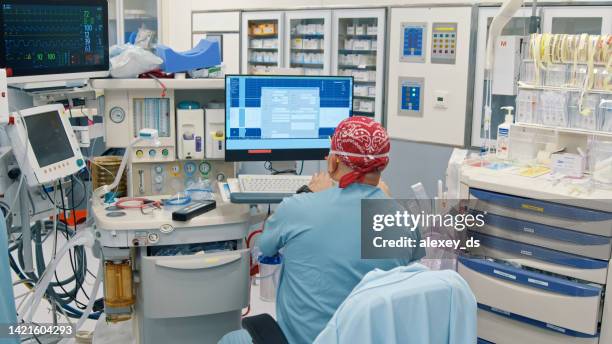 anesthesiologist looking at a patient's vital signs monitor during surgery - anaesthetic stock pictures, royalty-free photos & images