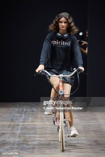 Model rides a bicycle on the runway at the Rebekka Ruétz show during the Mercedes-Benz Fashion Week Berlin Spring Summer 2023 at Telegraphenamt on...