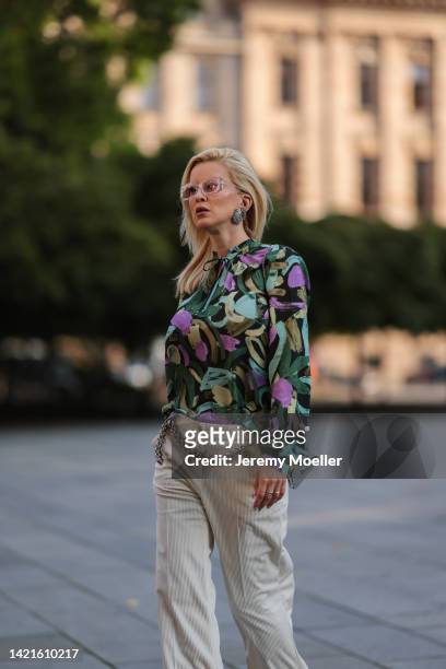 Palina Kozyrava is seen wearing Valentino shades, silver large earrings, colorful flower pattern blouse from Brax, beige cord fabric pants from Brax...