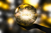 fortune telling 2023 with a crystal ball in a hand, festive atmosphere for happy new year party or award ceremony or other celebrations, 3d illustration