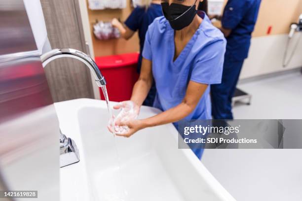 unrecognizable female nurse with mask washes hands thoroughly - schoonschrobben stockfoto's en -beelden