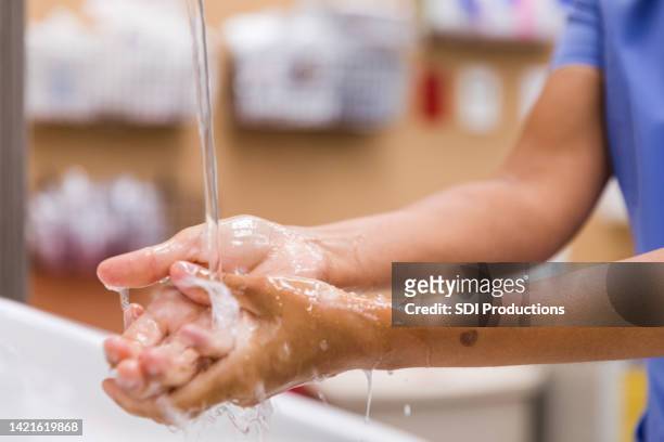 cerrar el agua que se derrama sobre las manos del trabajador médico - hand washing fotografías e imágenes de stock