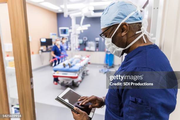 vor dem betreten des untersuchungsraums überprüft der arzt die testergebnisse des patienten - triage stock-fotos und bilder