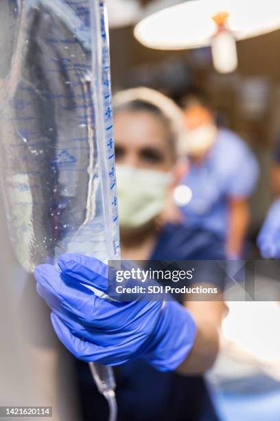 unrecognizable nurse adjusts iv in operating room - triage stock pictures, royalty-free photos & images