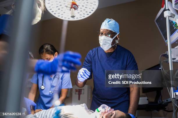 diverse er team moves quickly to assist injured woman - african tribal images stock pictures, royalty-free photos & images