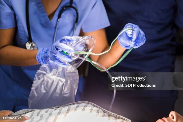 krankenschwester setzt bewusstlose patientin mit sauerstoffmaske auf - oxygen mask stock-fotos und bilder
