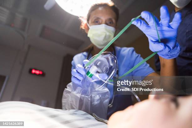 doctor stretches the straps on the oxygen mask - breathing device stock pictures, royalty-free photos & images