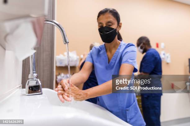 nurse sanitizes her hands - nurse washing hands stock pictures, royalty-free photos & images