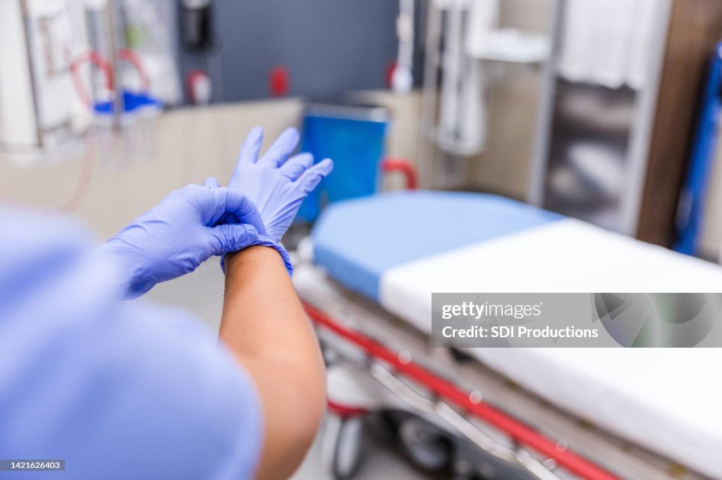 Rear view of medical staff putting gloves on