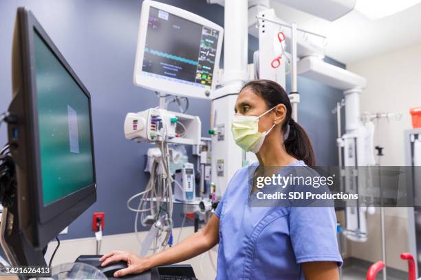 nurse uses computer to review medical chart - critical care bildbanksfoton och bilder