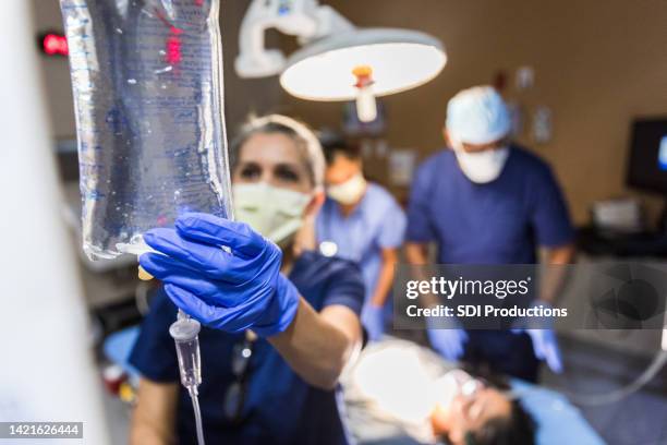 el médico revisa la bolsa intravenosa - ahora fotografías e imágenes de stock