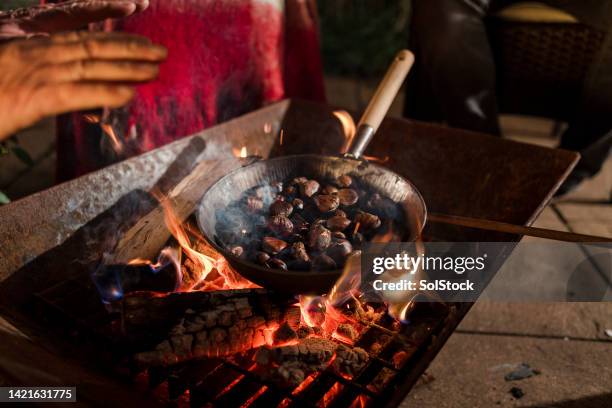 rösten von kastanien auf einem feuer - maroni stock-fotos und bilder