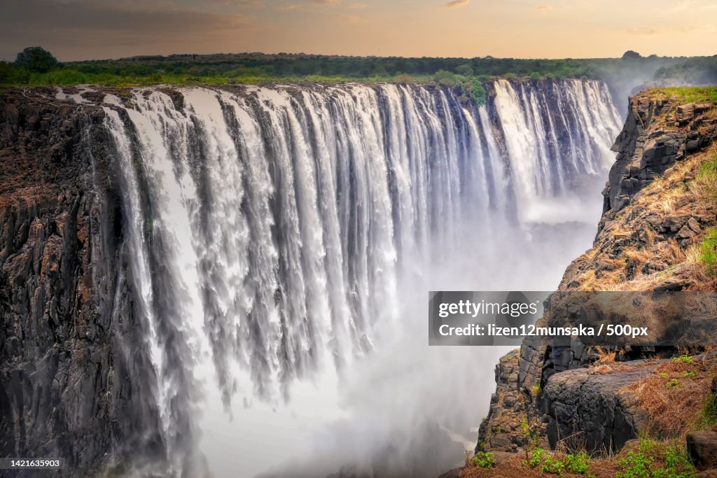 Scenic view of waterfall against sky during sunset,Zambia