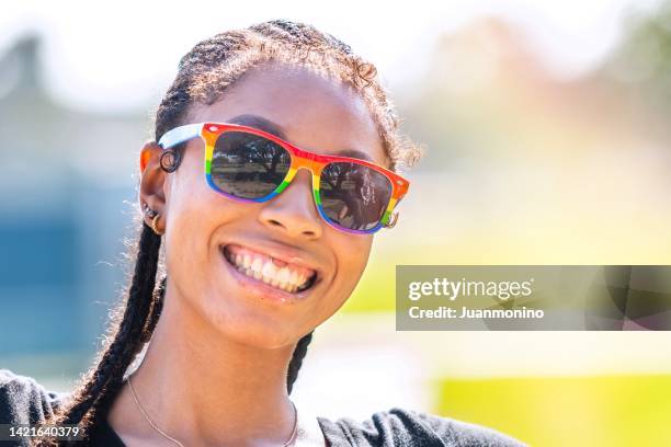 smiling afro-latinx young woman looking at the camera - gay sunglasses stock pictures, royalty-free photos & images