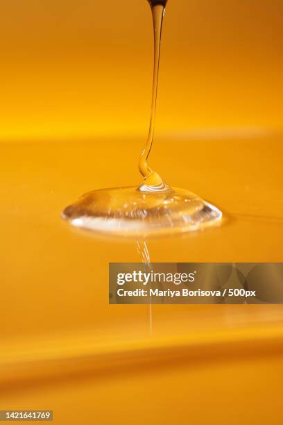 a drop of body gel or shampoo pouring from above on a yellow saturated - jojoba nut stock pictures, royalty-free photos & images