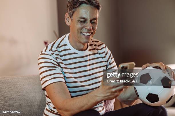 cheerful mature man watching a football match at home - sportsman channel stock pictures, royalty-free photos & images