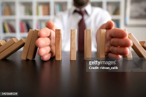 businessman stop domino effect. risk management and insurance concept - wooden shield stock pictures, royalty-free photos & images