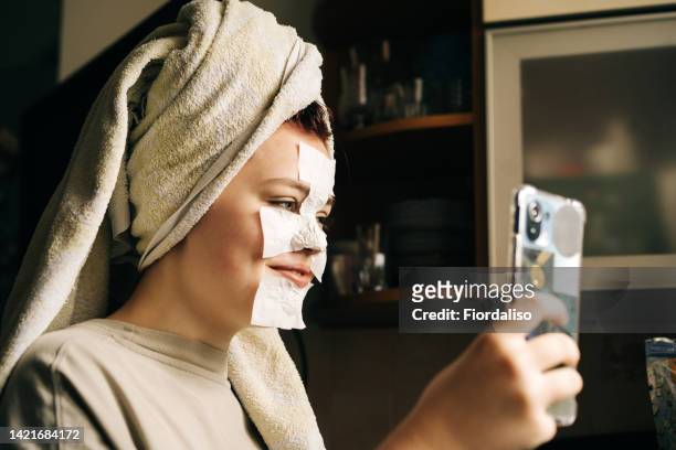 close-up portrait of a young teenage girl doing facial treatments - nose mask fotografías e imágenes de stock