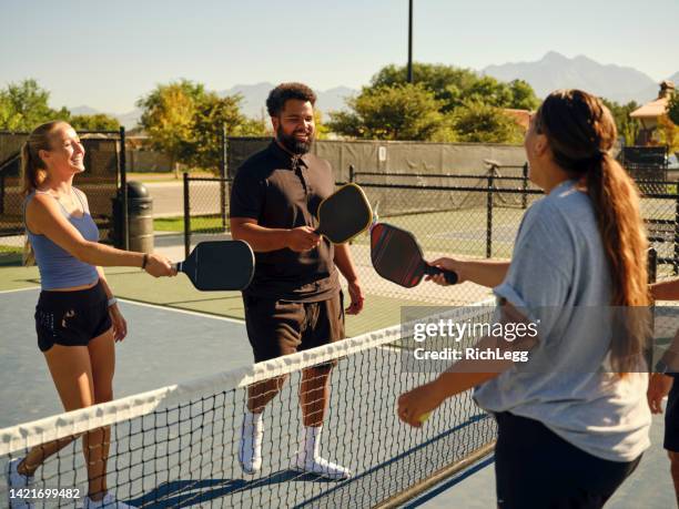 young adults playing pickleball on a public court - mixed doubles stockfoto's en -beelden