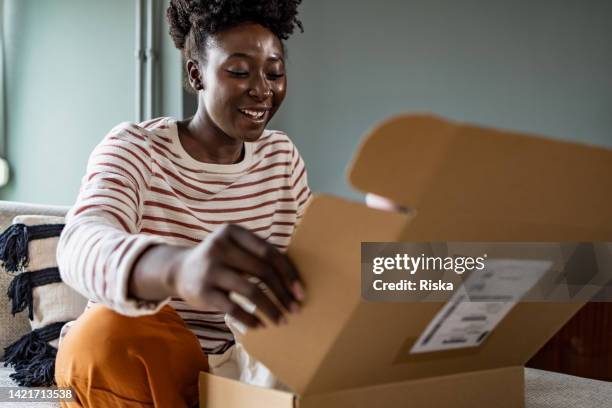 smiling african american woman opening her online delivery box - opening package bildbanksfoton och bilder