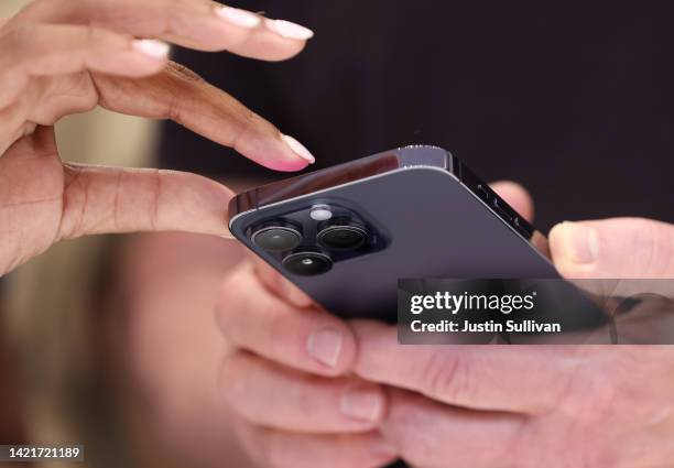 Attendees examine a brand new iPhone 14 Pro during an Apple special event on September 07, 2022 in Cupertino, California. Apple CEO Tim Cook unveiled...