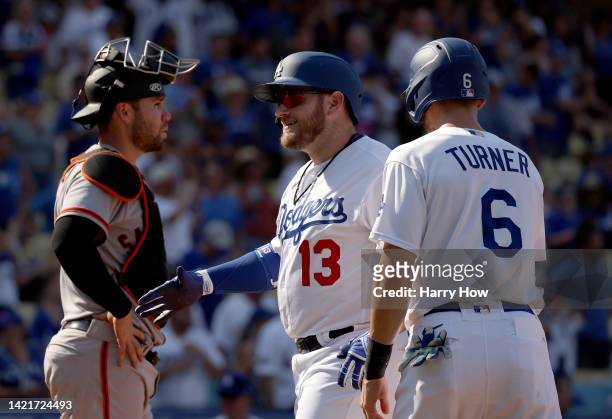 Max Muncy of the Los Angeles Dodgers reacts to his three run homerun between Austin Wynns of the San Francisco Giants and Trea Turner, to take a 7-3...