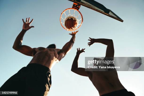 young athletic boys playing basketball, throwing a ball into the hoop - basketball hoop stockfoto's en -beelden