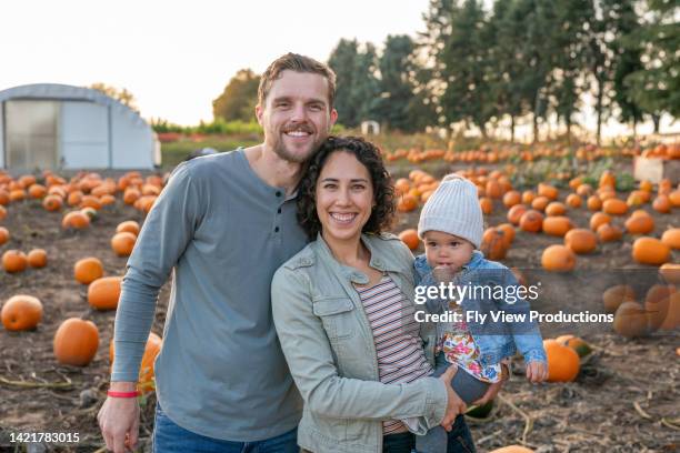 young mixed race family at pumpkin patch together - asian mother and daughter pumpkin stockfoto's en -beelden