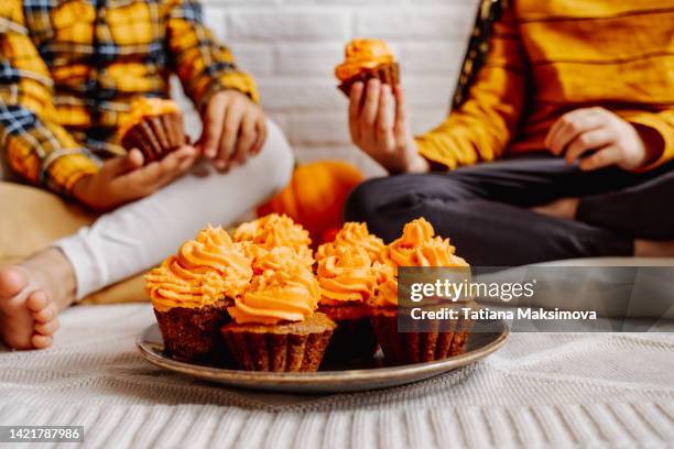 plate with orange cupcakes close-up. two little boys with cupcakes celebrate halloween. - dessert lifestyle stock pictures, royalty-free photos & images