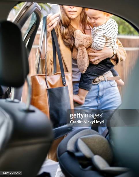mother carefully gets her baby boy out of the car - purse contents stock pictures, royalty-free photos & images