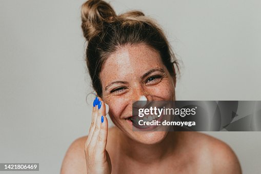 顔に保湿クリームを塗る幸せなそばかすのある女性 顔に保湿クリームを塗る幸せなそばかすのある女性