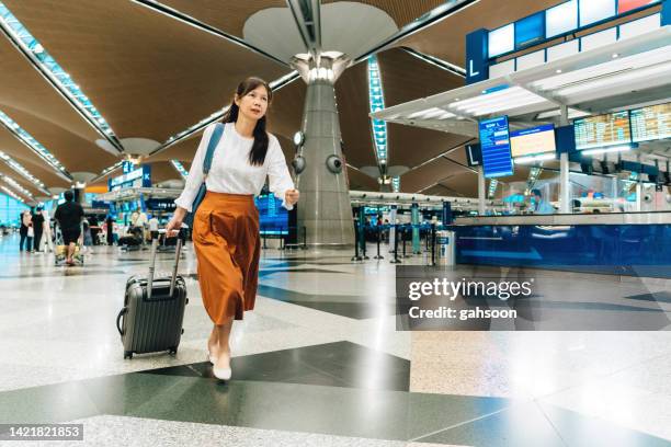 weibliche reisende, die am flughafen läuft - kuala lumpur airport stock-fotos und bilder