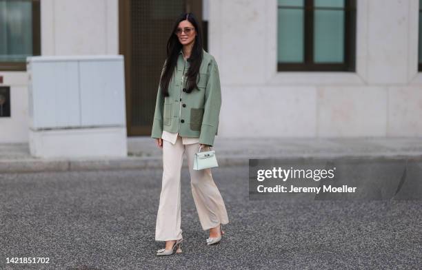 Leo Eberlin is seen wearing brown COS shades, beige silk two-piece from Reformation, a green Loewe jacket, green fyzz Hermès Mini bag, gold Hermès...