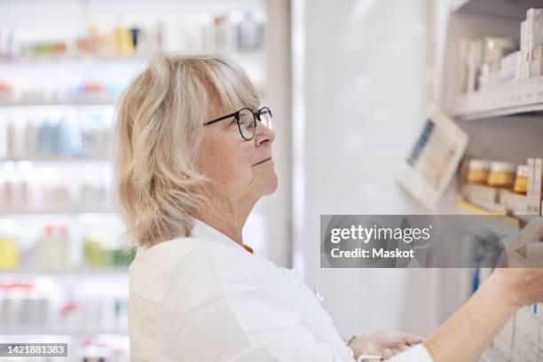 elderly female pharmacist examining medicines at pharmaceutical industry - mid length hair 個照片及圖片檔