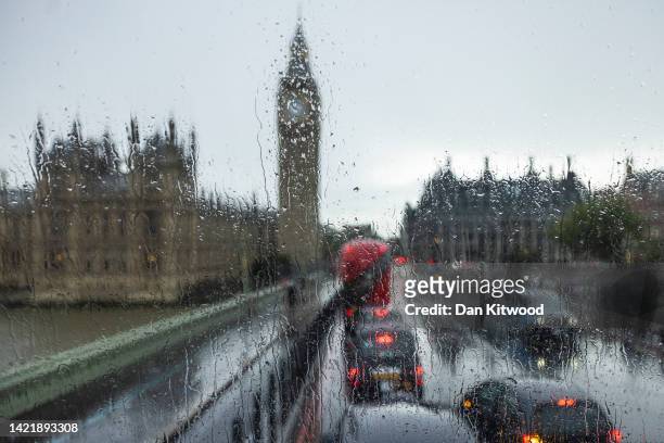 Rain streaks across a bus window passing the Houses of Parliament, as British Prime Minister Liz Truss announces her plans on capping energy bills,...