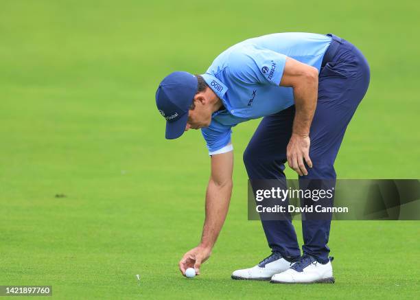 Billy Horschel of The United States replaces his ball due to preferred lies being in force due to the wet conditions for his second shot on the...