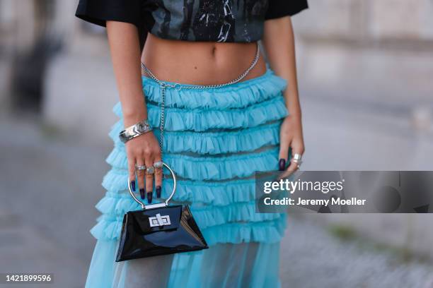 Alina Kossan is seen wearing black printed cropped oversize Bondy t-shirt, blue transparent tulle ruffled long skirt, black leather mini bag from...