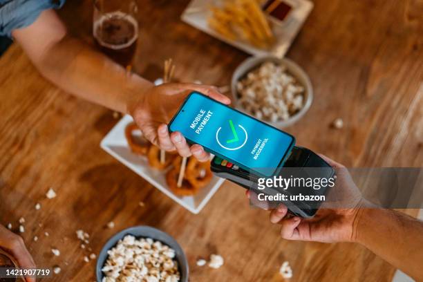 young man paying via contactless channel by mobile banking application - beer pump stock pictures, royalty-free photos & images