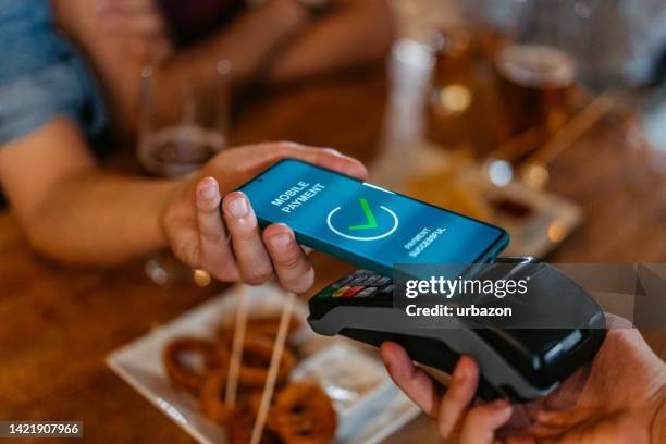 young man paying via contactless channel by mobile banking application - mobile payment stock pictures, royalty-free photos & images