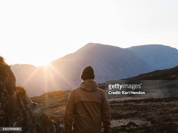 a hiker stands looking at the sunset in the lake district, cumbria - montanhas cumbrianas - fotografias e filmes do acervo