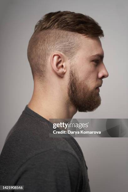 portrait of a handsome man in profile with beard and short hair style, he has grey t-shirt and confident view on grey background. the man looks away. - male man portrait one person business confident background stock pictures, royalty-free photos & images