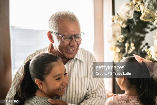 granddaughters greeting grandfather on christmas at home - mexican christmas stock pictures, royalty-free photos & images