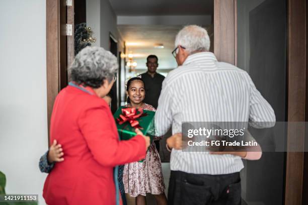 family greeting grandparents on christmas at home - returning gift stock pictures, royalty-free photos & images