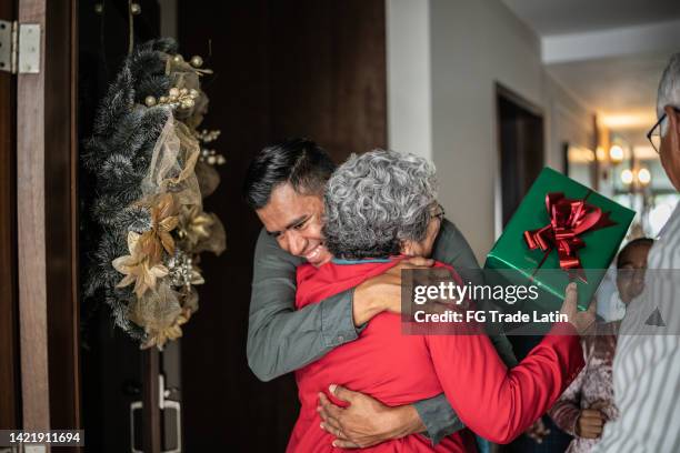 son greeting mother on christmas at home - mexican christmas stock pictures, royalty-free photos & images