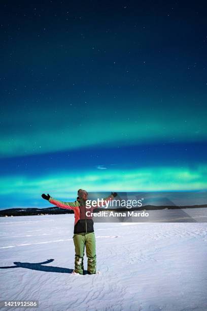 one women throwing her hands into the sky with northern lights in the background. - el fin stock-fotos und bilder