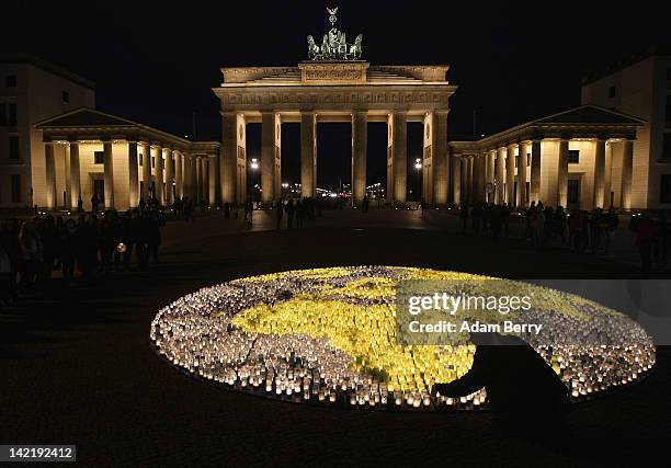 Volunteer lights one of 5000 blue and green candles in an eight-meter shape of Planet Earth in front of the Brandenburg Gate during Earth Hour 2012...