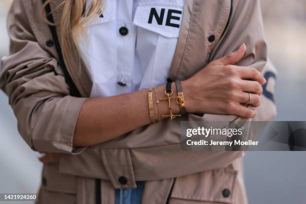 Alena Gerber wearing Chanel white cropped logo blouse and H&M denim pants & Balenciaga beige rain coat & Hermes and Cartier Love Bracelet arm candy...