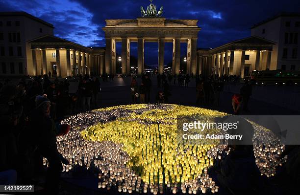 Volunteers light some of 5000 blue and green candles in an eight-meter shape of Planet Earth in front of the Brandenburg Gate during Earth Hour 2012...