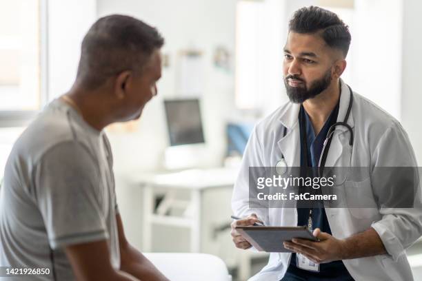 männlicher arzt, der mit einem patienten spricht - male doctor man patient stock-fotos und bilder